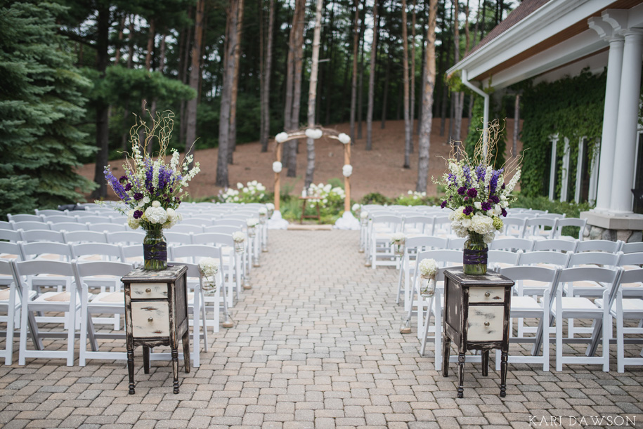 Rustic and elegant ceremony floral arrangements flank the aisle for this rustic elegant outdoor wedding ceremony in the woods l rustic branch arbor