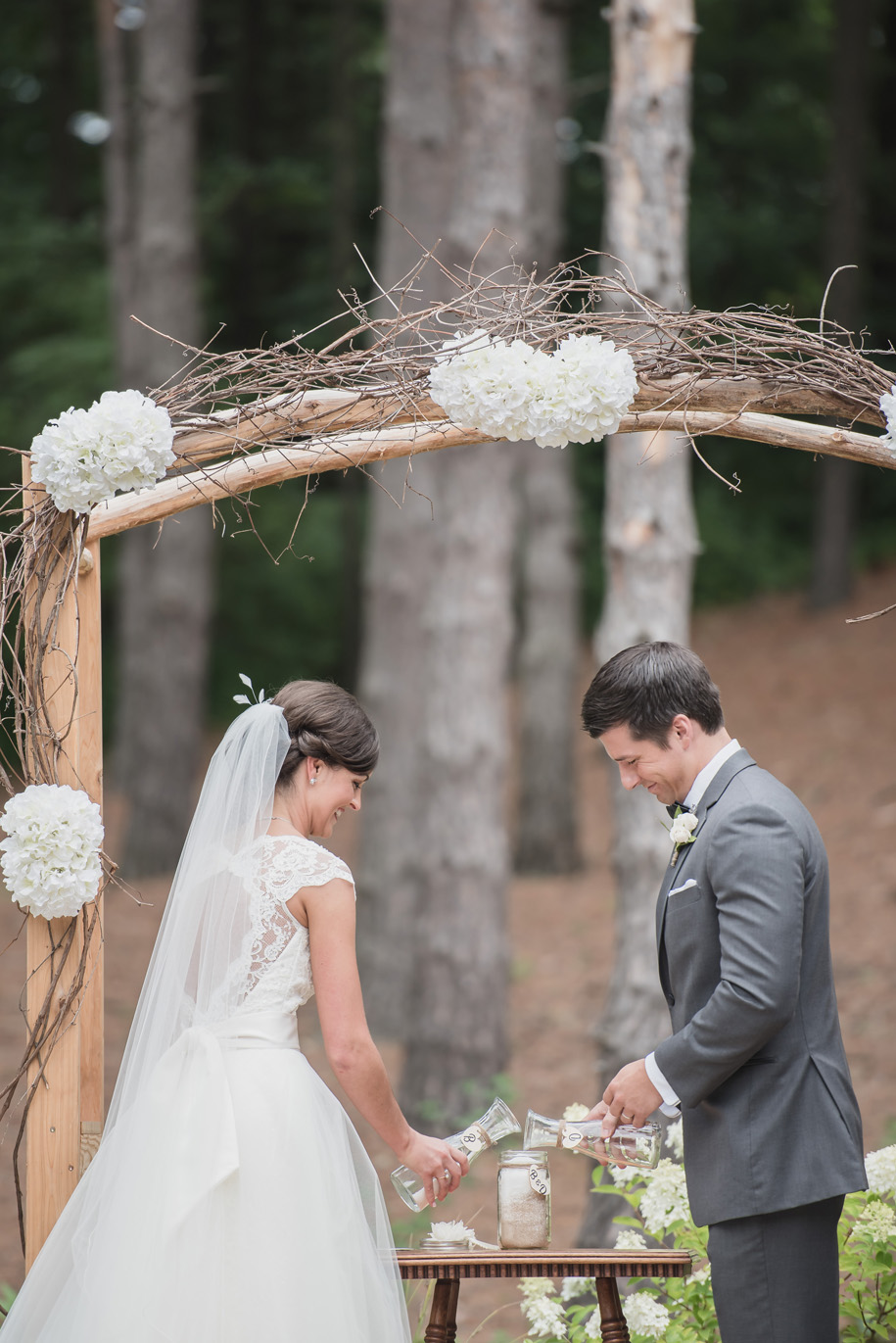 Rustic twig and branch arbor for a rustic elegant outdoor ceremony in the woods l Lace wedding dress and tulle skirt l Tuxedo l Bow tie l Sand ceremony
