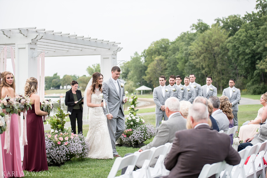 Bride and groom present their mother's with white roses during their shabby chic outdoor wedding ceremony at waldenwoods