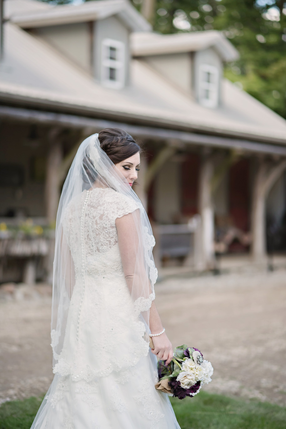 Stunning bride in her lace v-neck wedding gown with cap sleeve and high back lace l lace trimmed veil l Outdoor Inner Circle Estate Wedding by Kari Dawson
