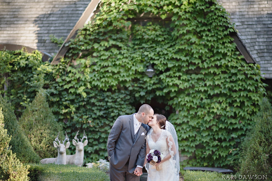 Bride and Groom kiss in front of the castle l Purple, Cream and Grey Wedding l Rustic and Romantic Outdoor Inner Circle Estate Wedding in the woods by Kari Dawson