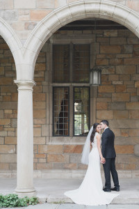 Elegant and timeless lace bodice wedding dress designed by the bride and her groom in an elegant and classic black suit and black tie at the University of Michigan Law Quad by Kari Dawson Photography