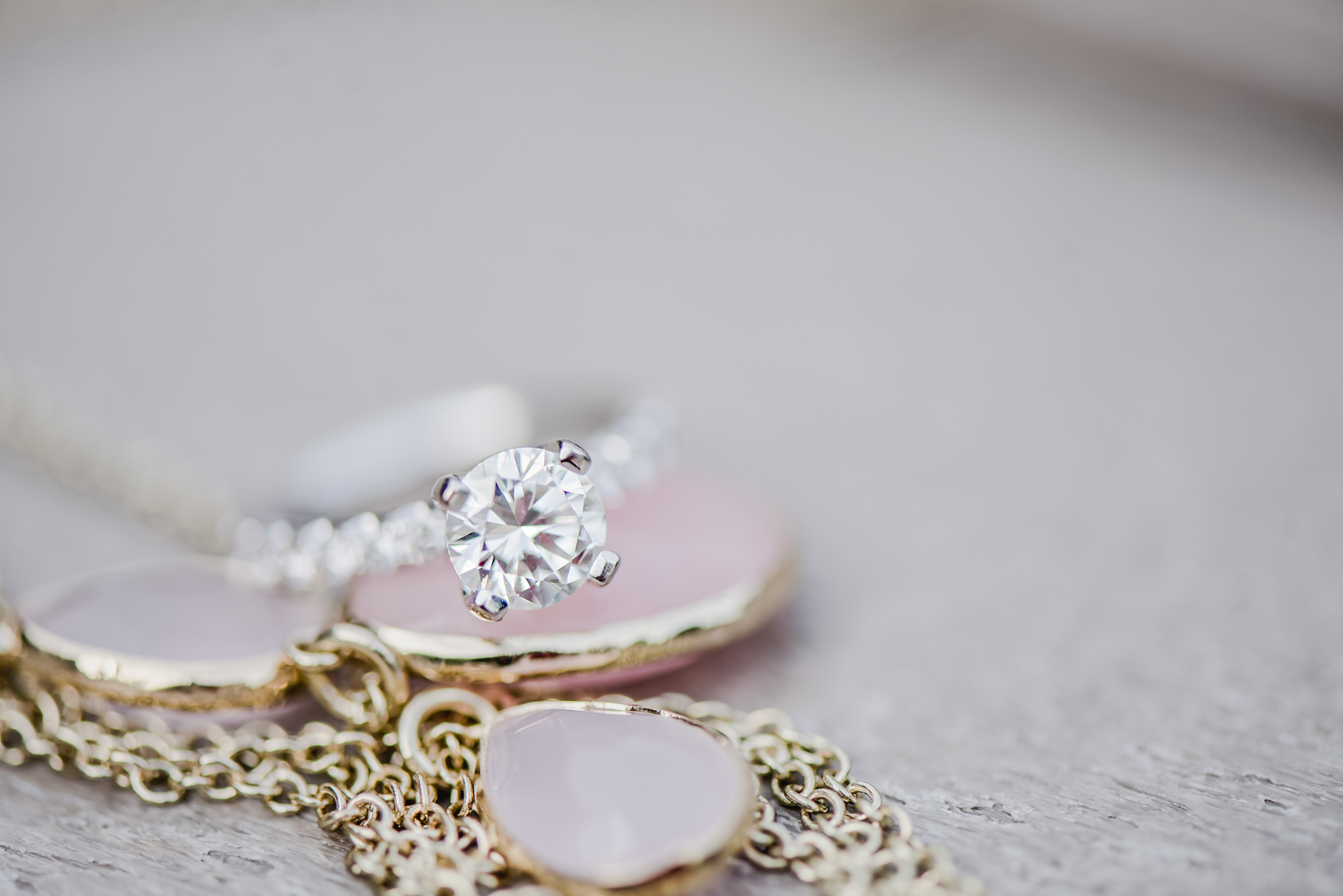 Gorgeous round diamond solitaire flanked on either side by pave' diamonds set in white gold. This engagement ring looks beautiful set agains the pink and gold. Summer engagement session in the woods by Kari Dawson Photography.