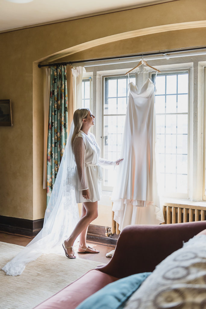 Bride admiring her dress moments before it's time to get dressed. This Black and white summer Meadow Brook Hall wedding in Rochester, Michigan is elegant, modern, romantic, yet unique, and classic. Provided by Kari Dawson, top-rated Rochester wedding photographer, and her team. 