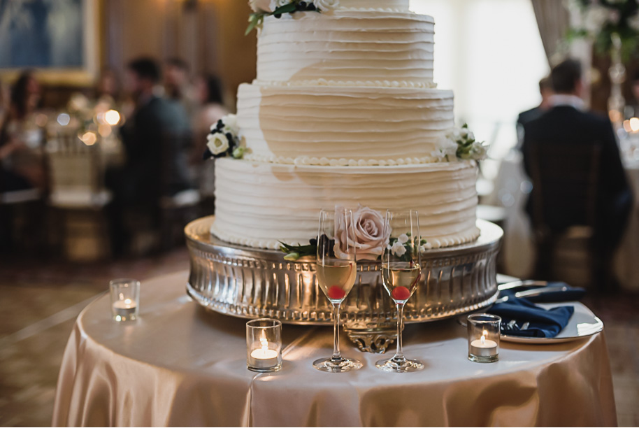 Five tier cream ruffled wedding cake adorned with blush colored roses. Sage and navy summer wedding at the Detroit Athletic Club in Detroit, Michigan provided by Kari Dawson, top-rated Detroit wedding photographer, and her team.