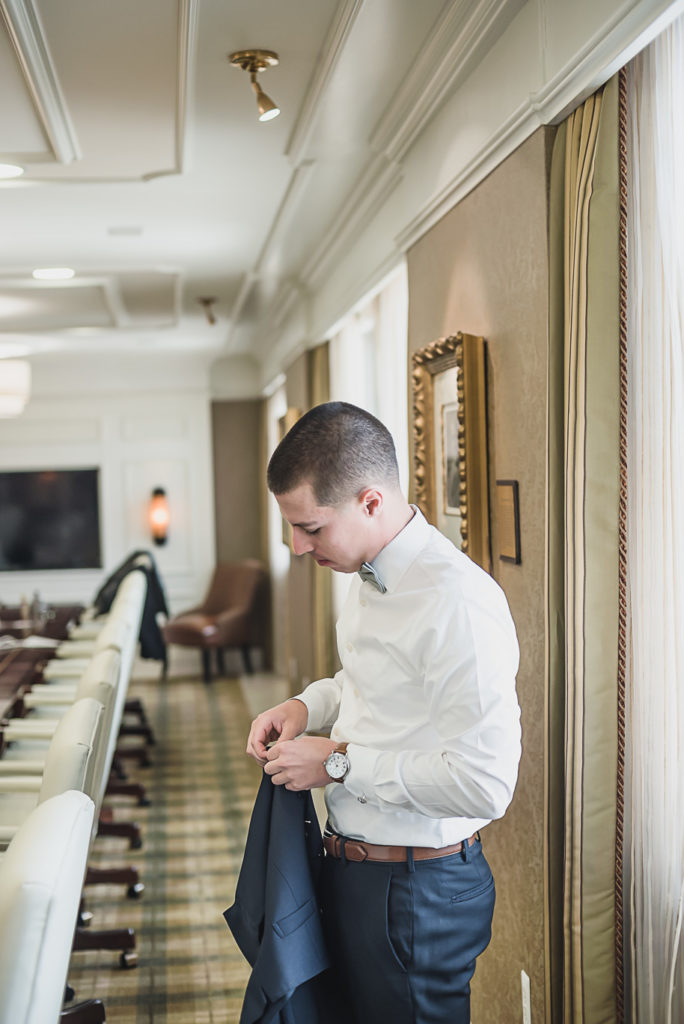 Groom getting ready for his Sage and navy summer wedding at the Detroit Athletic Club in Detroit, Michigan provided by Kari Dawson, top-rated Detroit wedding photographer, and her team.