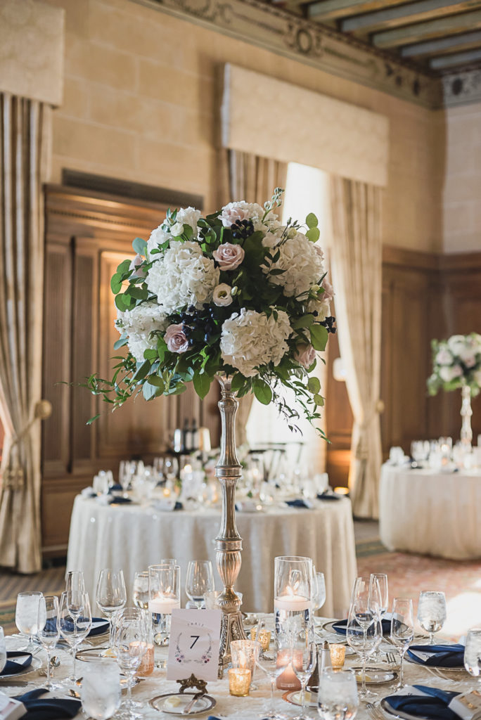 Unstructured oblong floral centerpieces combined with floral centerpieces on top of tall mercury vases in blush and cream. Sage and navy summer wedding at the Detroit Athletic Club in Detroit, Michigan provided by Kari Dawson, top-rated Detroit wedding photographer, and her team.