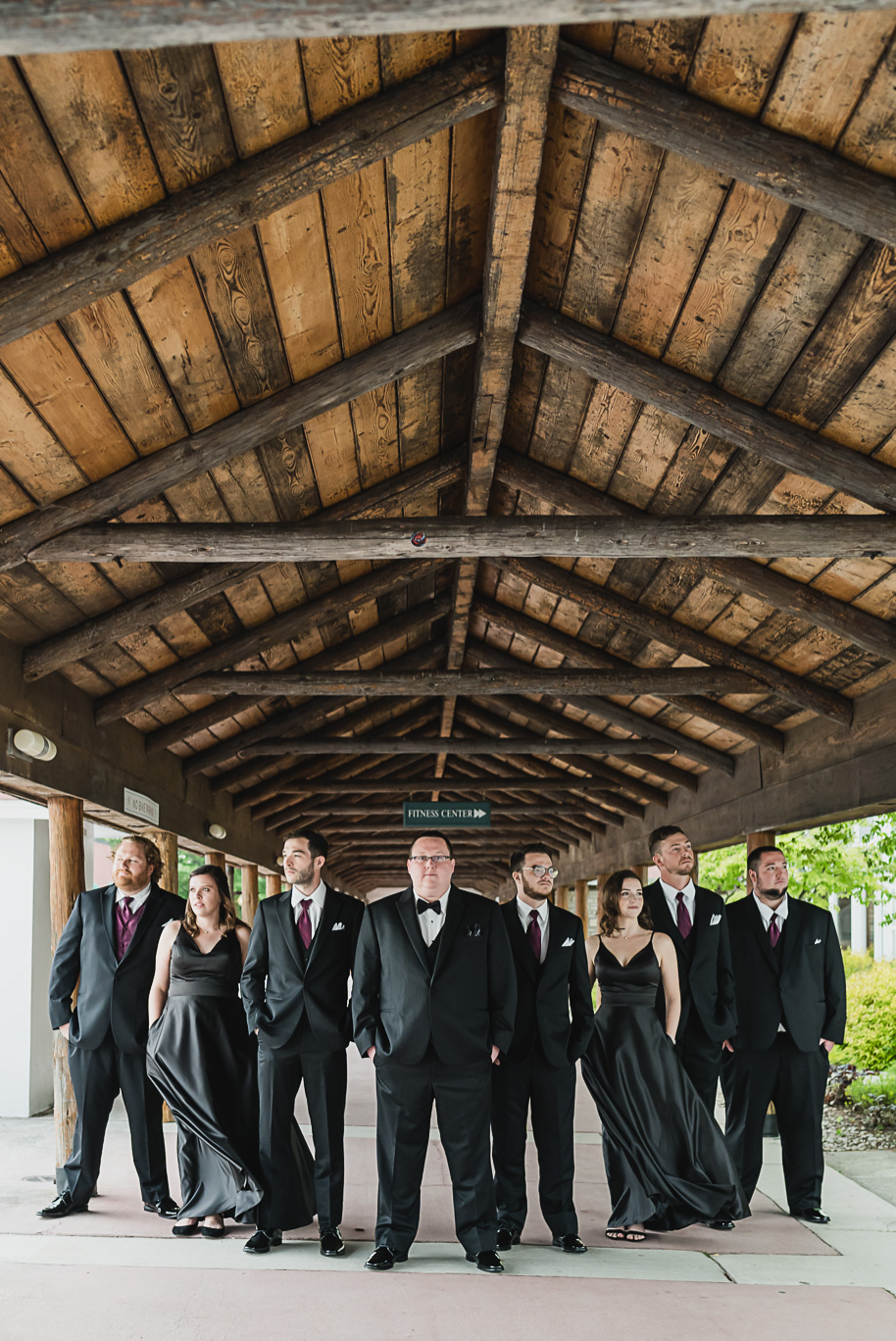 Black tuxedo and black floor length bridesmaid dresses. Twigs & Branches unstructured peony wedding bouquet. An intimate destination Mackinac Island wedding at Mission Point Resort with a cranberry and black color palette provided by Kari Dawson, top-rated Northern Michigan wedding photographer, and her team.