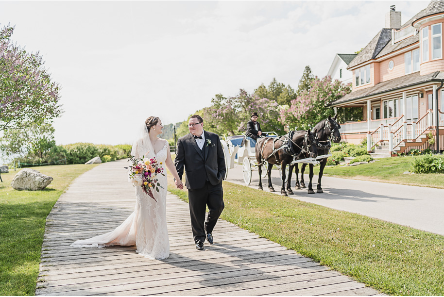 Bride and Groom carriage wedding day photos on Mackinac Island. An intimate destination Mackinac Island wedding at Mission Point Resort with a cranberry and black color palette provided by Kari Dawson, top-rated Northern Michigan wedding photographer, and her team.