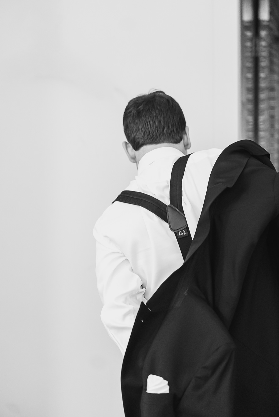 Groom putting on his tuxedo jacket before the black-tie Jewish wedding at Bay Pointe Golf Club in West Bloomfield, Michigan.