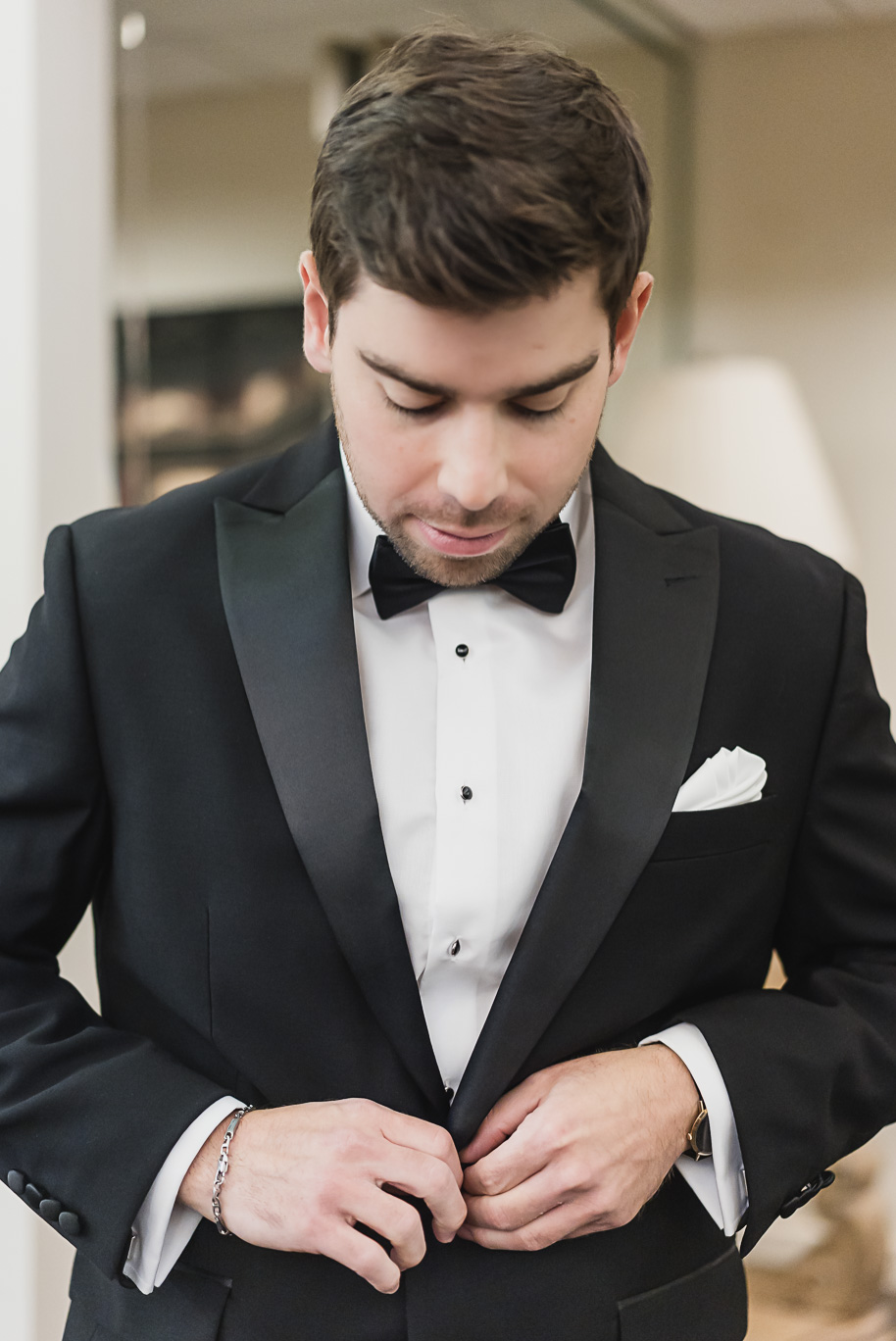 Groom putting on his tuxedo jacket before the black-tie Jewish wedding at Bay Pointe Golf Club in West Bloomfield, Michigan.
