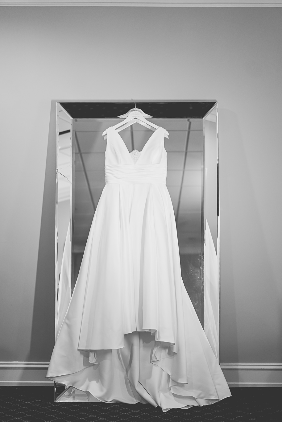 Classic white bridal gown displayed on a full-length mirrored hanger at Bay Pointe Golf Club before the Jewish wedding ceremony.