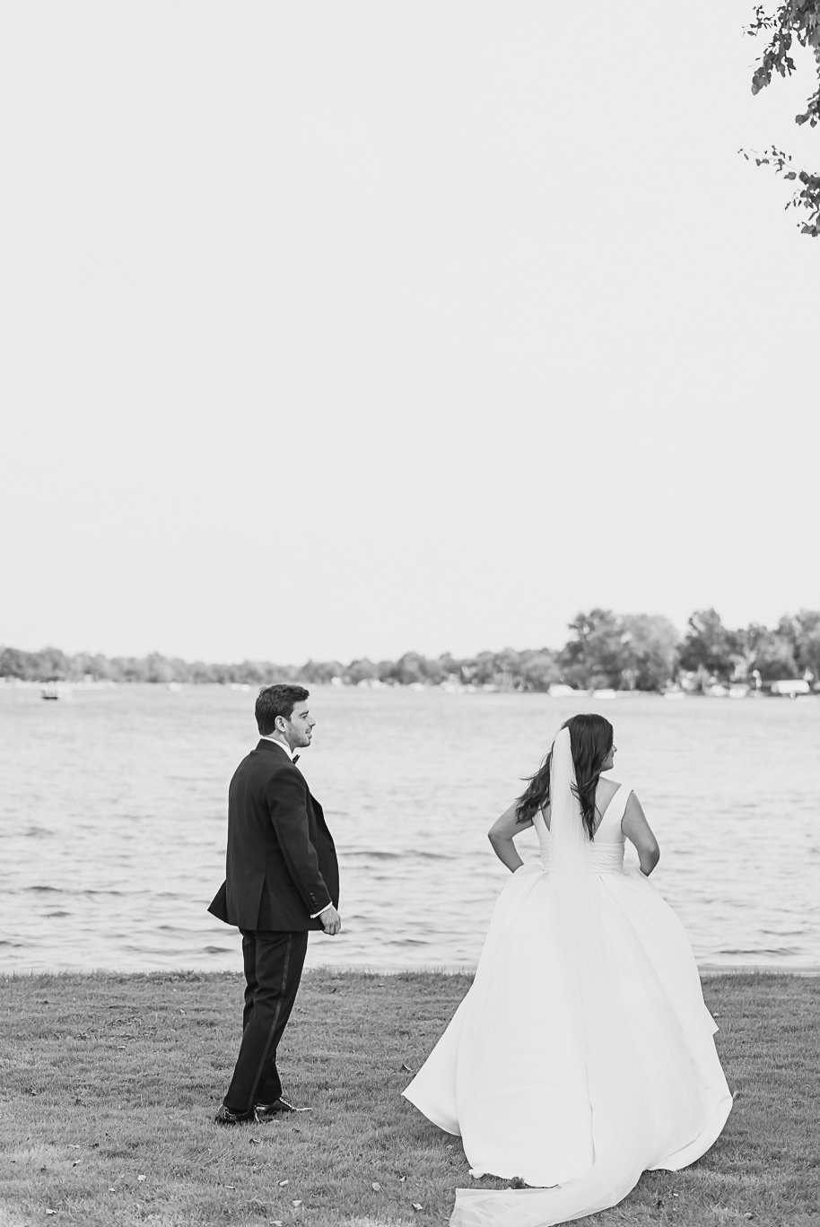 A timeless black-and-white photograph of the bride and groom standing along the shoreline at Bay Pointe Golf Club.