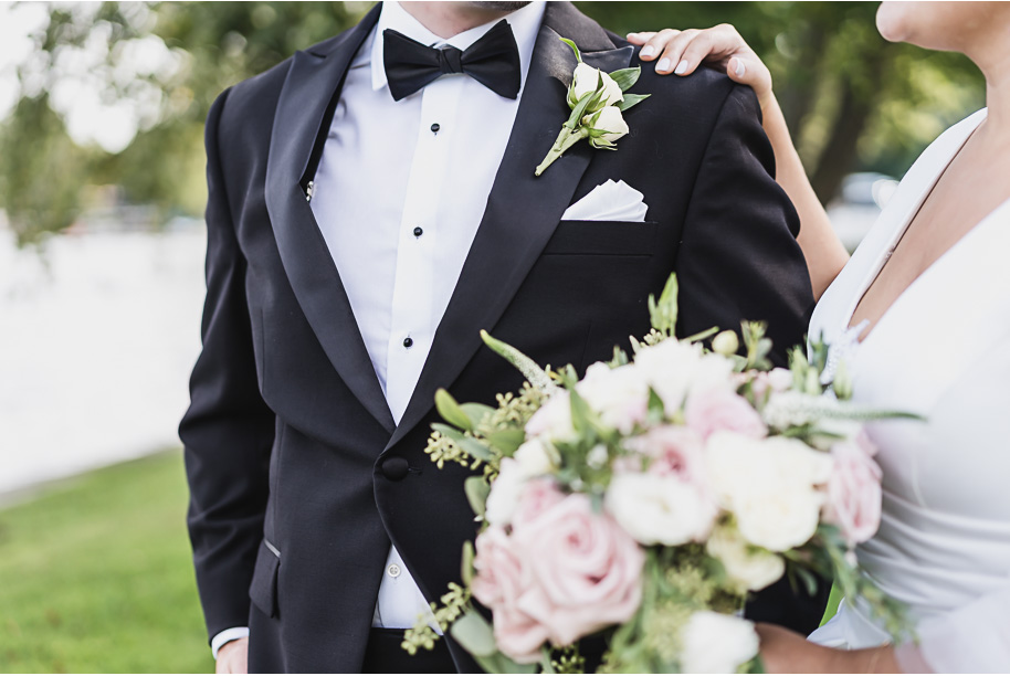 A romantic bouquet featuring blush and ivory roses, lisianthus, and lush greenery carried by the bride in her timeless white gown.
