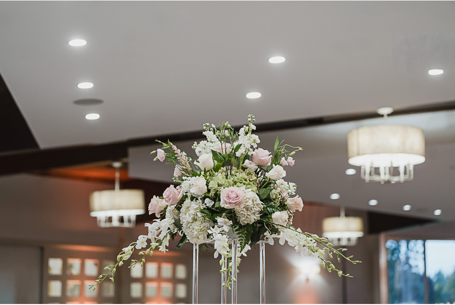 Romantic Bay Pointe Golf Club reception with tall floral centerpieces, soft candlelight, and clear chiavari chairs creating an elegant ballroom atmosphere.
