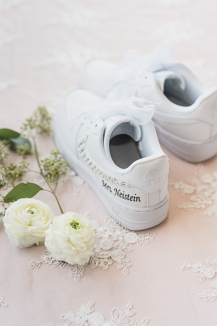 Custom white Nike sneakers with “Mrs. Neistein” embroidery, styled with ranunculus blooms before Bay Pointe Jewish wedding.