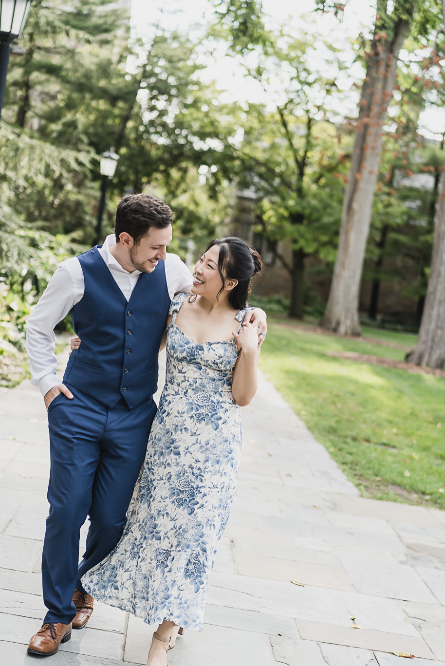 Laughing engaged couple strolling through the historic University of Michigan Law Quad, styled in coordinated blue and white outfits for their engagement photos.