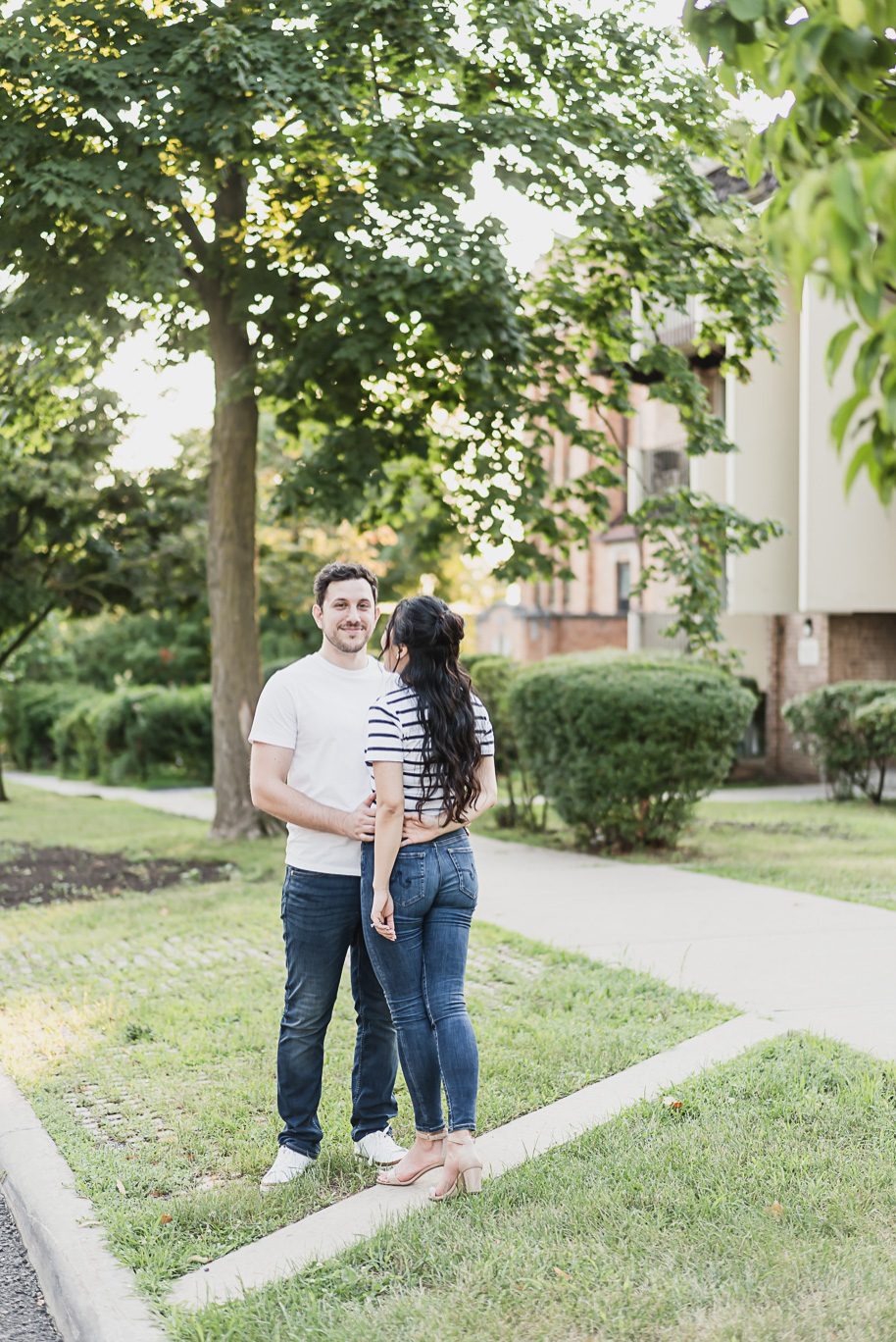 Sweet candid on a tree-lined street near Ann Arbor, highlighting casual summer romance during a Michigan Law Quad engagement.