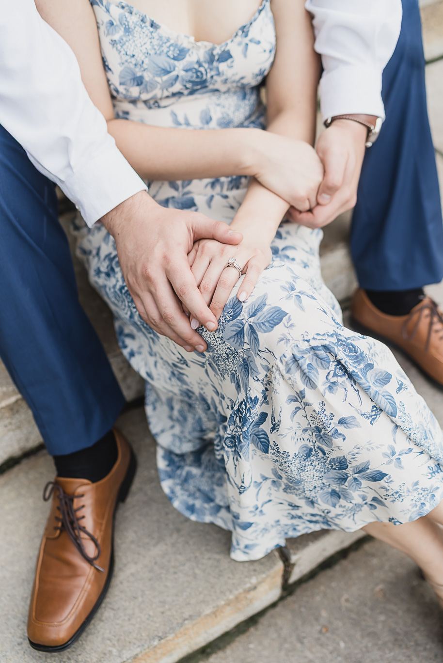 Close-up of Linda’s engagement ring as she holds Alex’s hand during their Michigan Law Quad engagement photos, with her blue floral dress adding timeless elegance.