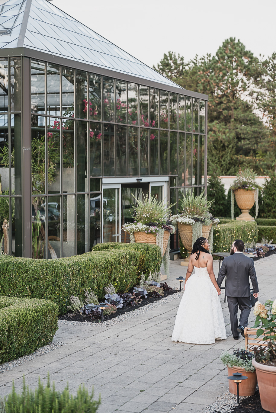 An elegant fall Planterra Conservatory wedding captured by Kari Dawson + Co in Bloomfield Hills, Michigan. This Euro-inspired greenhouse celebration featured lush floral design, golden candlelight, and heartfelt vows beneath the glass canopy. Perfect inspiration for couples dreaming of a romantic Michigan wedding surrounded by nature and timeless architecture.