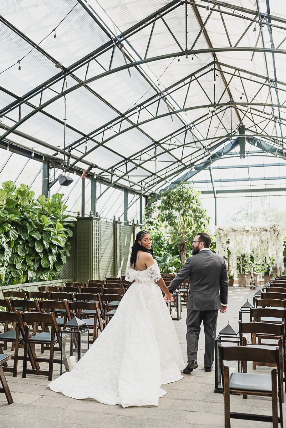 An elegant fall Planterra Conservatory wedding captured by Kari Dawson + Co in Bloomfield Hills, Michigan. This Euro-inspired greenhouse celebration featured lush floral design, golden candlelight, and heartfelt vows beneath the glass canopy. Perfect inspiration for couples dreaming of a romantic Michigan wedding surrounded by nature and timeless architecture.