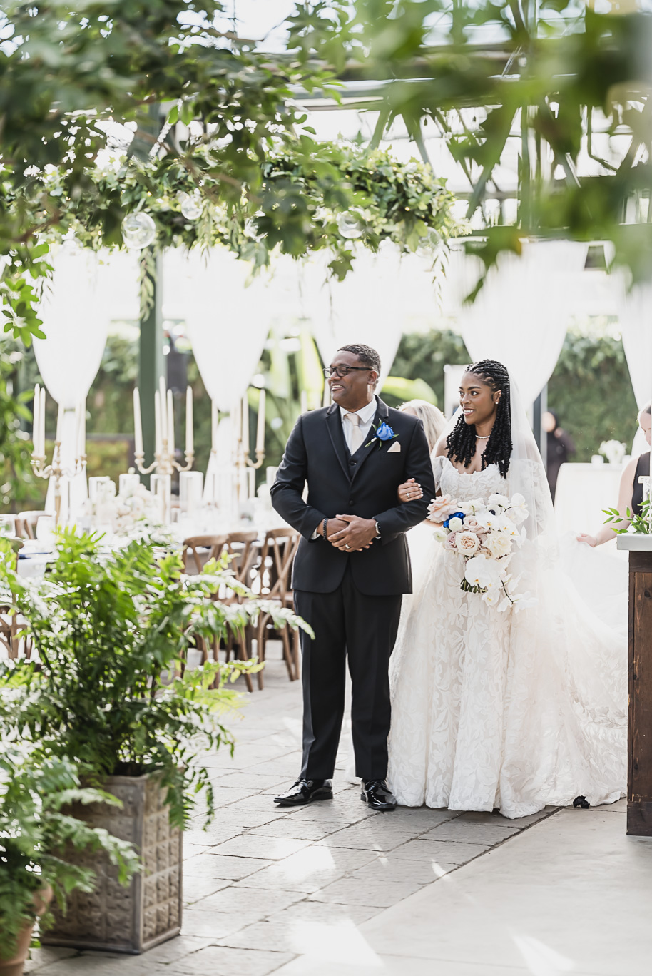 An elegant fall Planterra Conservatory wedding captured by Kari Dawson + Co in Bloomfield Hills, Michigan. This Euro-inspired greenhouse celebration featured lush floral design, golden candlelight, and heartfelt vows beneath the glass canopy. Perfect inspiration for couples dreaming of a romantic Michigan wedding surrounded by nature and timeless architecture.