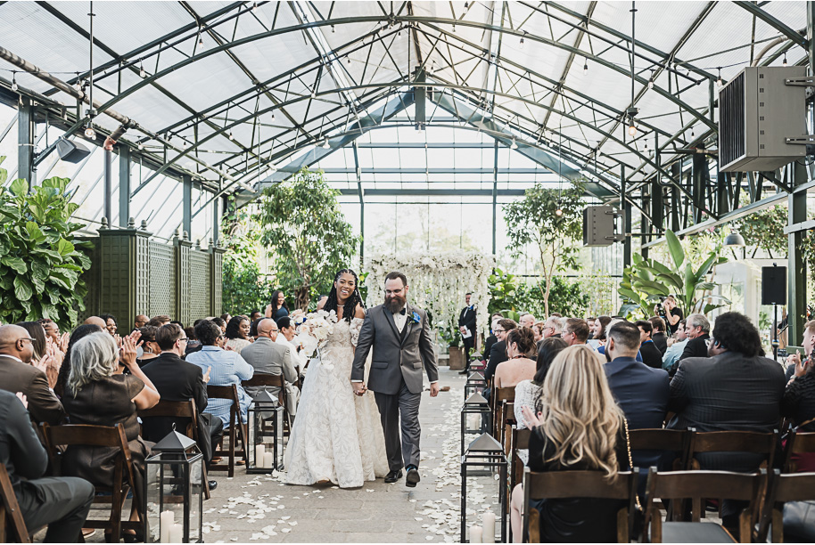 An elegant fall Planterra Conservatory wedding captured by Kari Dawson + Co in Bloomfield Hills, Michigan. This Euro-inspired greenhouse celebration featured lush floral design, golden candlelight, and heartfelt vows beneath the glass canopy. Perfect inspiration for couples dreaming of a romantic Michigan wedding surrounded by nature and timeless architecture.