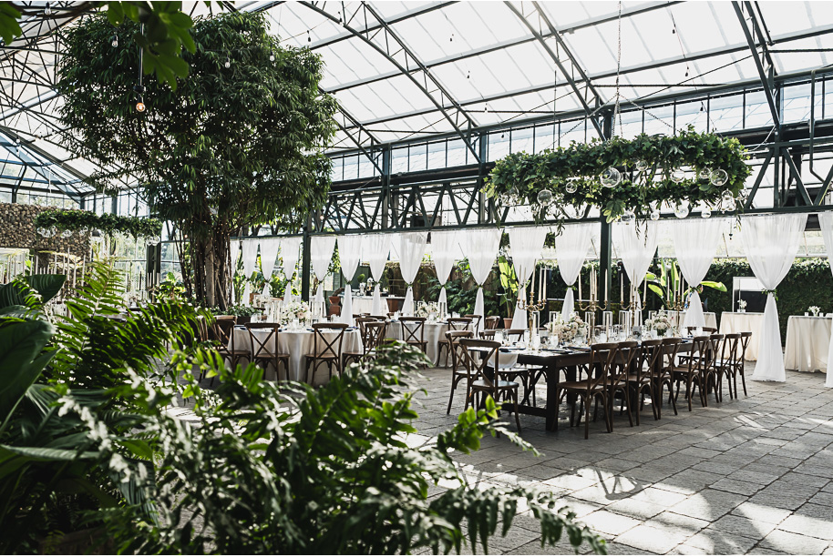 An elegant fall Planterra Conservatory wedding captured by Kari Dawson + Co in Bloomfield Hills, Michigan. This Euro-inspired greenhouse celebration featured lush floral design, golden candlelight, and heartfelt vows beneath the glass canopy. Perfect inspiration for couples dreaming of a romantic Michigan wedding surrounded by nature and timeless architecture.