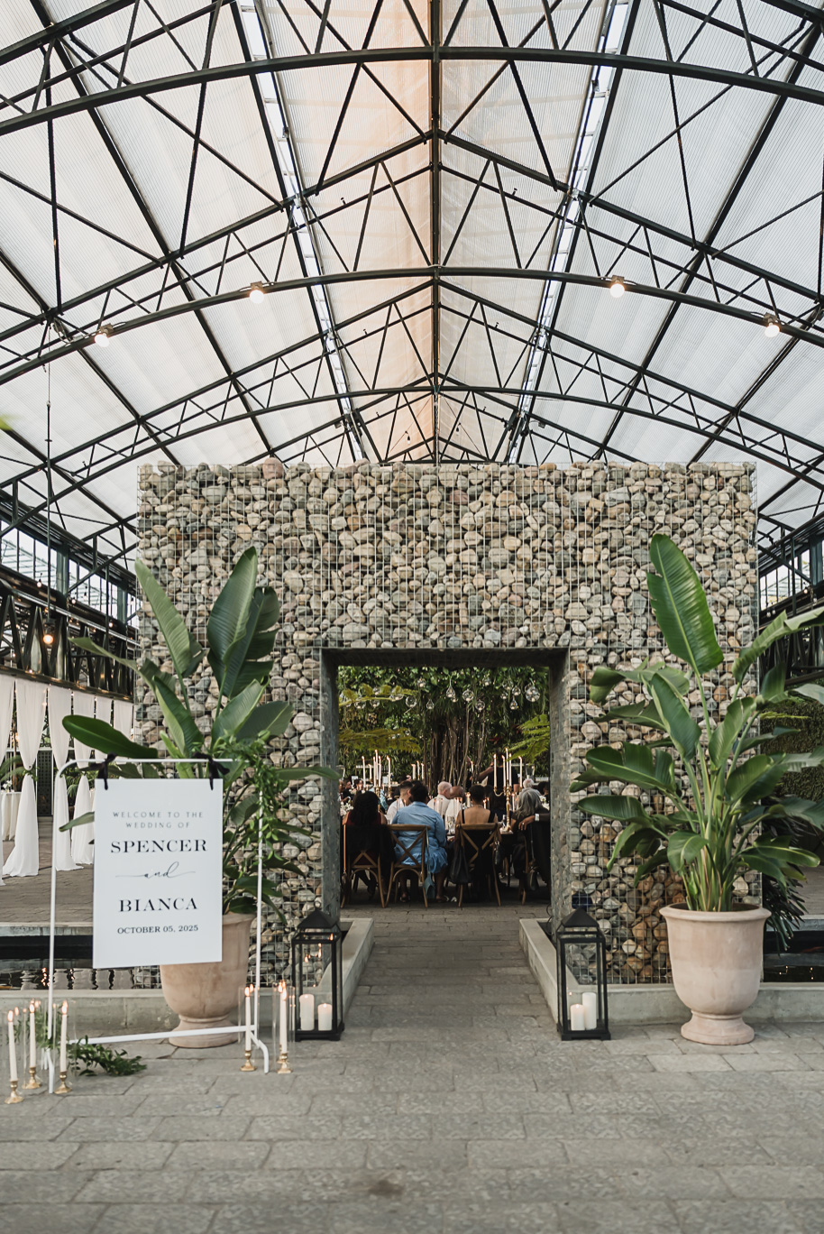 An elegant fall Planterra Conservatory wedding captured by Kari Dawson + Co in Bloomfield Hills, Michigan. This Euro-inspired greenhouse celebration featured lush floral design, golden candlelight, and heartfelt vows beneath the glass canopy. Perfect inspiration for couples dreaming of a romantic Michigan wedding surrounded by nature and timeless architecture.