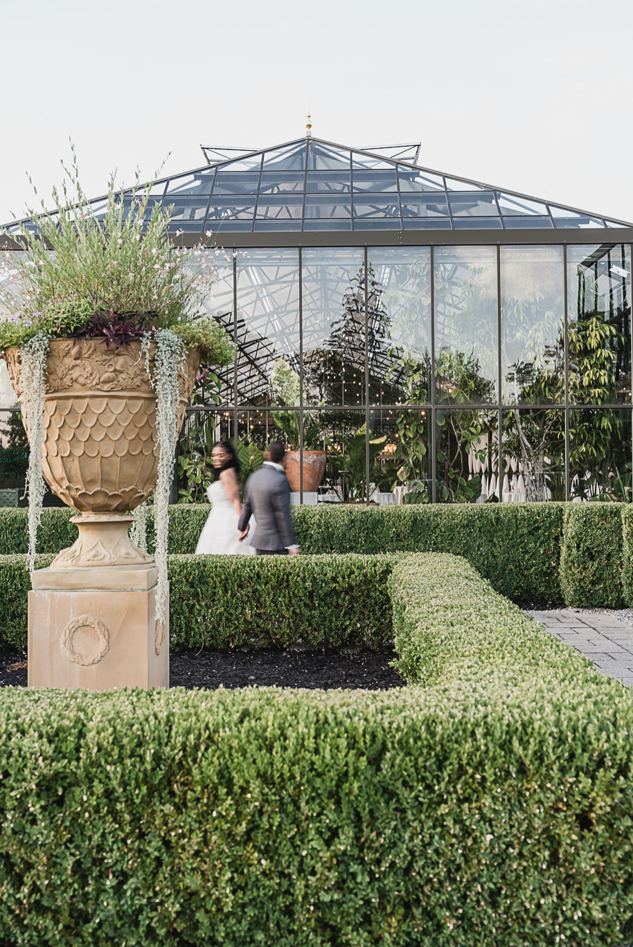 An elegant fall Planterra Conservatory wedding captured by Kari Dawson + Co in Bloomfield Hills, Michigan. This Euro-inspired greenhouse celebration featured lush floral design, golden candlelight, and heartfelt vows beneath the glass canopy. Perfect inspiration for couples dreaming of a romantic Michigan wedding surrounded by nature and timeless architecture.