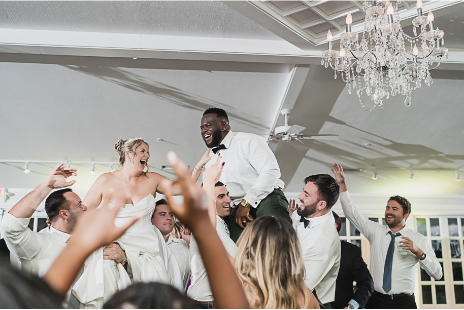 Joyful reception dancing at Castle Farms in Northern Michigan, captured by Kari Dawson + Co. The newlyweds are lifted into the air surrounded by cheering guests beneath crystal chandeliers, celebrating with pure energy and connection.