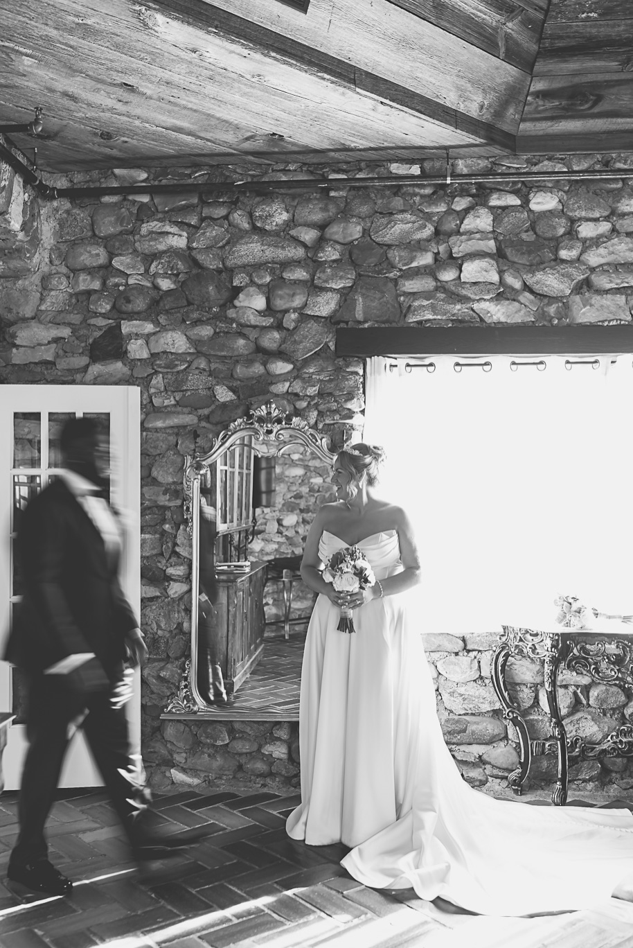 “Bride stands in front of a stone wall holding her bouquet before the ceremony at Castle Farms in Charlevoix, Michigan. Captured by Kari Dawson + Co, this timeless black and white editorial wedding portrait reflects quiet anticipation and elegance.