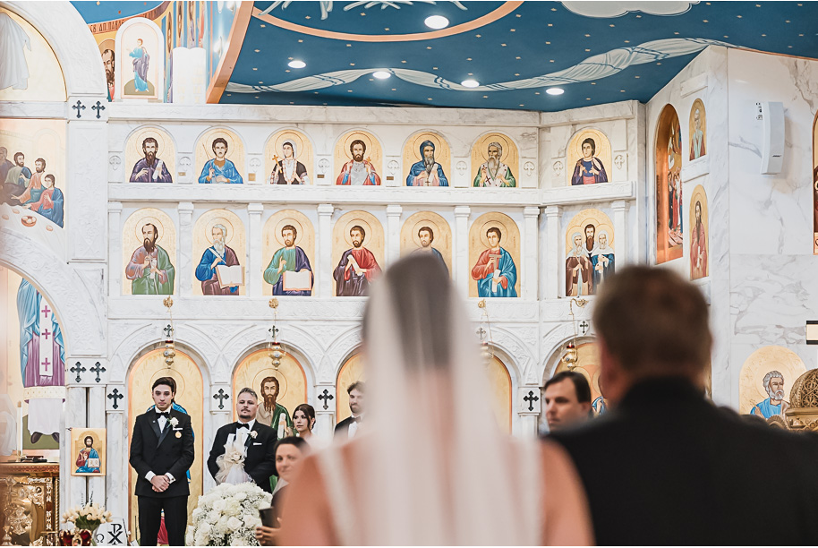 Bride and groom share a kiss during their Macedonian wedding ceremony inside Nativity of the Virgin Mary, surrounded by vibrant domed ceilings and biblical murals.
