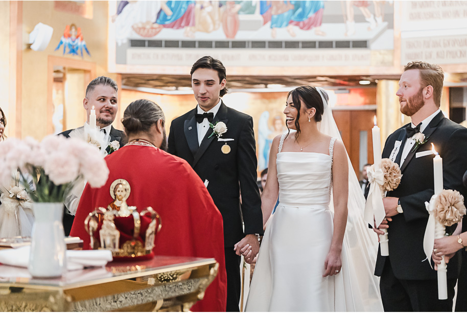 Bride and groom share a kiss during their Macedonian wedding ceremony inside Nativity of the Virgin Mary, surrounded by vibrant domed ceilings and biblical murals.
