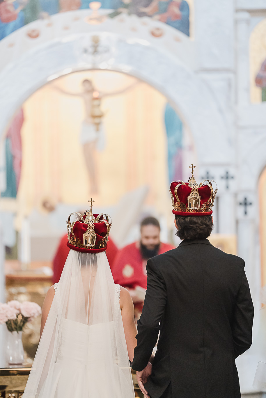 Bride and groom share a kiss during their Macedonian wedding ceremony inside Nativity of the Virgin Mary, surrounded by vibrant domed ceilings and biblical murals.
