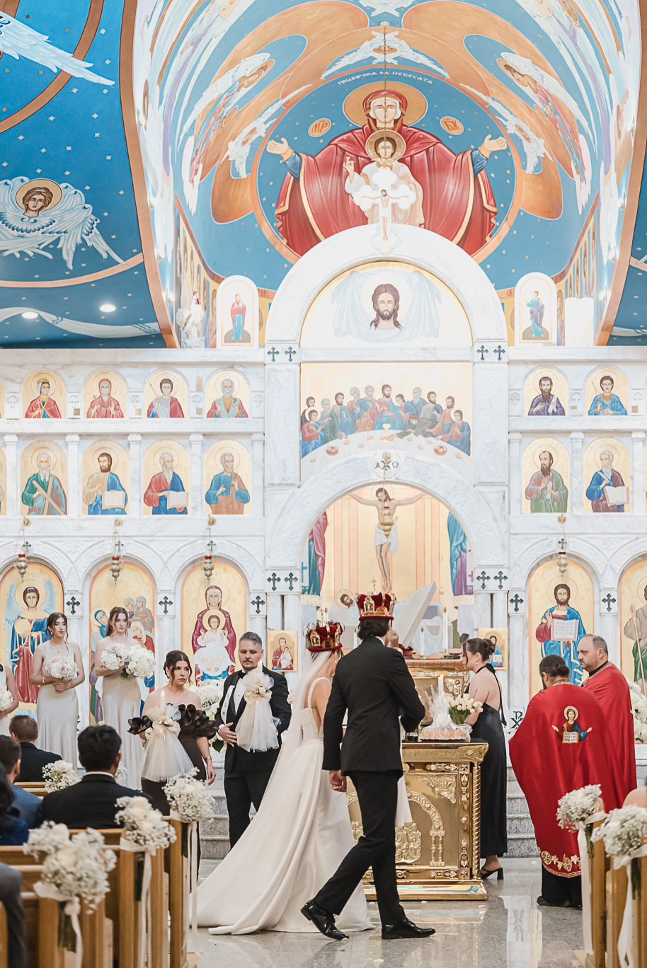 Bride and groom share a kiss during their Macedonian wedding ceremony inside Nativity of the Virgin Mary, surrounded by vibrant domed ceilings and biblical murals.
