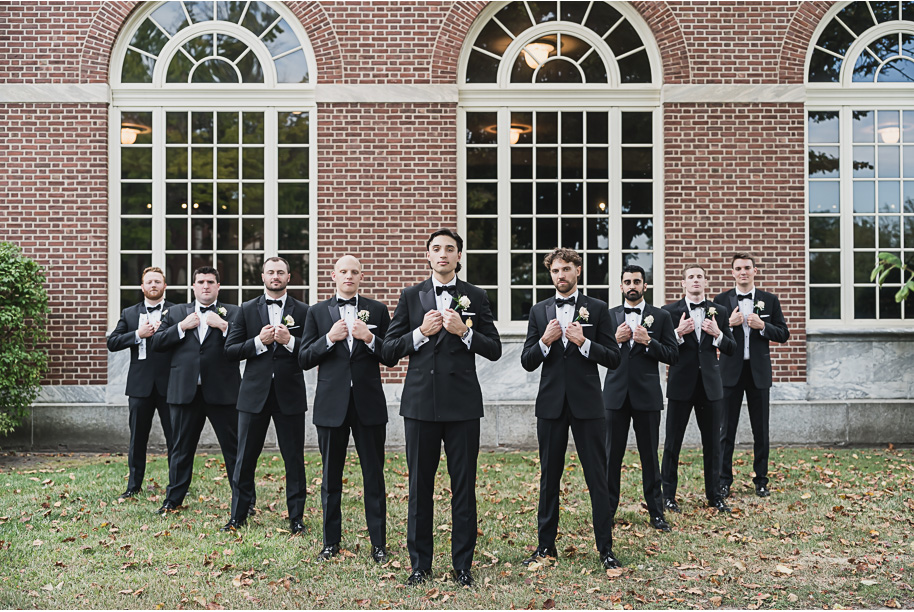 Bride and groom stand with their wedding party outside Lovett Hall, groomsmen in black tuxedos and bridesmaids in champagne gowns.