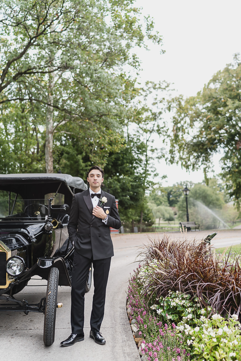 Bride and groom stand beside a black Model T at Greenfield Village for portraits, a nod to Detroit’s history.
