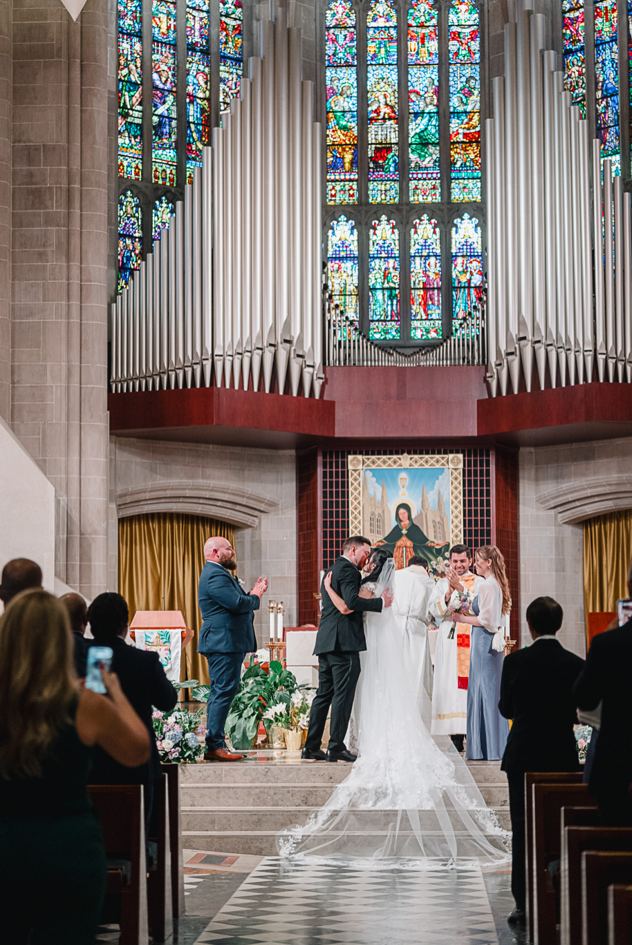 The couple's first kiss at the Cathedral of the Most Blessed Sacrament after their spring Detroit wedding ceremony. 