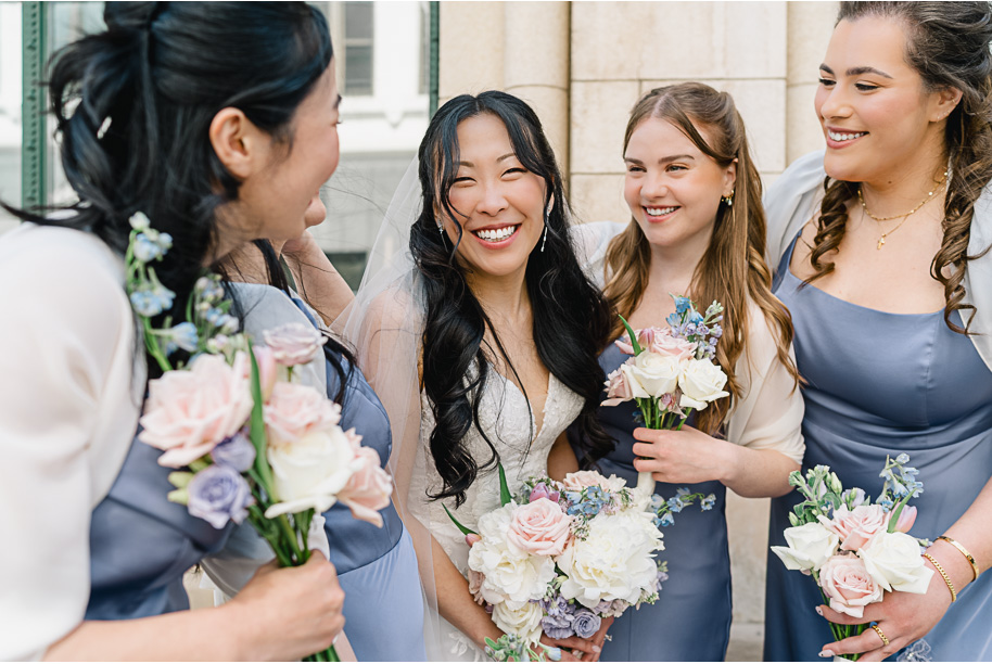 A bride and her bridesmaids in lavender satin birdy grey dresses with pastel colored bouquets having fun in downtown Detroit after the Detroit wedding ceremony. 