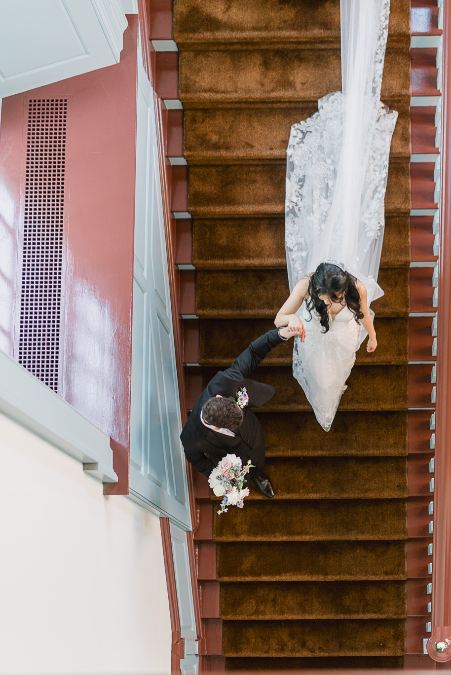 The bride and groom coming down the iconic staircase in the blue room of for their Henry Ford Museum wedding.
