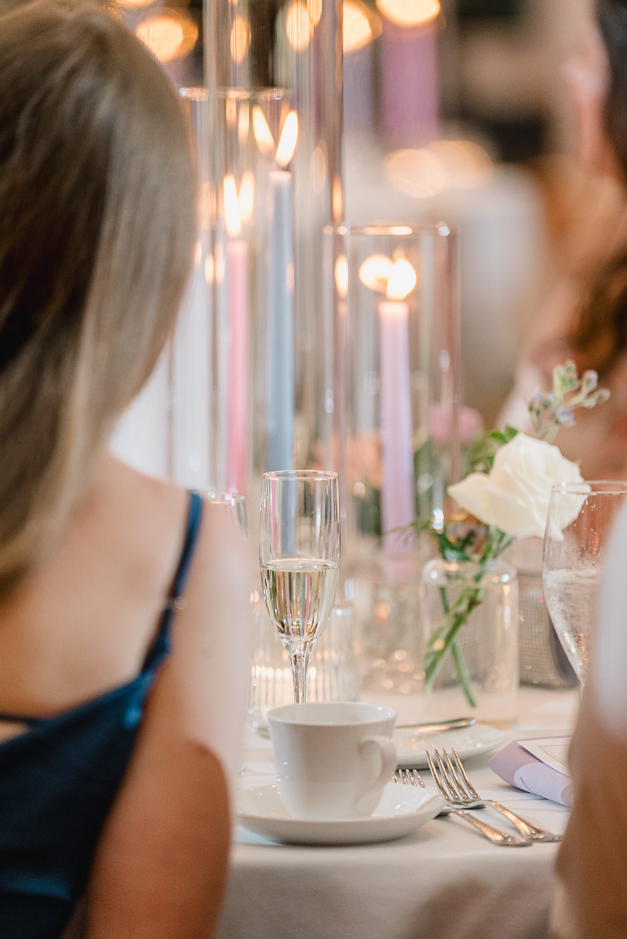 Guests mingle and drink champagne while enjoying the pastel color palette, candle sticks in hurricane glass, and bud vases filled with lush florals at this Henry Ford Museum wedding.